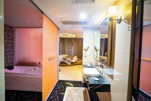 A modern hotel bathroom with a bathtub, a large mirror, and a vanity with a sink. - Heng Rong Hotel (FANGCHENGGANG)