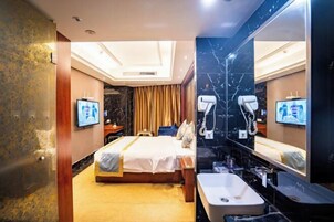 Una habitación de hotel con una cama, un espejo grande, un lavabo y un televisor.