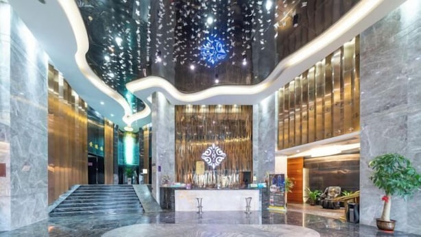 Un vestíbulo amplio con suelo de mármol, una recepción central y un elemento decorativo en el techo.