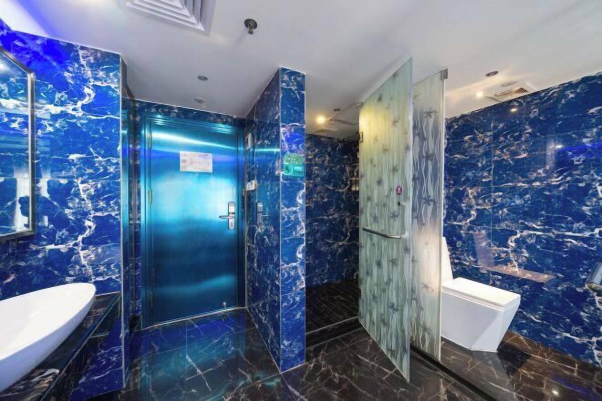 A modern bathroom with a marble design, a sink, a toilet, and a shower area.