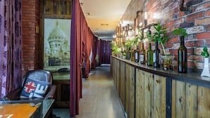 Un pasillo estrecho con una barra de madera a un lado, con botellas y plantas.