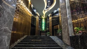 Una escalera de mármol conduce a un vestíbulo con un diseño moderno en el techo e iluminación verde.