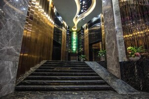 A marble staircase leading to a lobby with a modern ceiling design and green lighting.