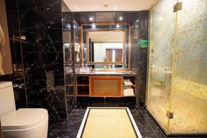 Ein modernes Badezimmer mit Marmorboden, einem großen Spiegel, einem Waschbecken und einer Duschkabine.