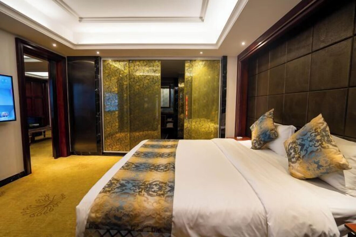 A hotel room with a large bed, a television, and a sliding door leading to a bathroom.