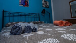 Une chambre à coucher avec un lit, un mur bleu, un tableau encadré, une lampe et un miroir.