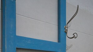 Une salle de bain avec une porte bleue, un porte-serviettes et une serviette qui y est accrochée.