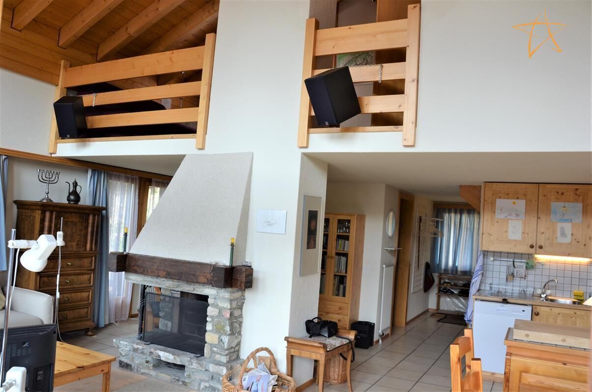 Un intérieur rustique avec une cheminée en pierre, des étagères en bois, un coin cuisine et un espace repas.