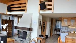 Un ambiente rustico con camino in pietra, mensole di legno, angolo cottura e zona pranzo.