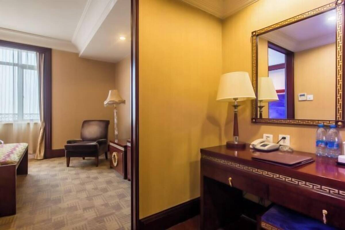 Een hotelkamer met een bed, een bureau, een stoel, een spiegel en een lamp.