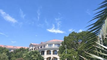 Un grand bâtiment doté de nombreux balcons, entouré d’arbres et surplombant un ciel dégagé.