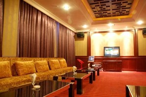 Une chambre d’hôtel avec une moquette rouge, un canapé, une télévision et un mur recouvert de panneaux en bois.