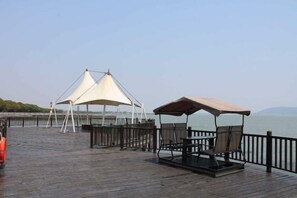 Une terrasse en bois avec des sièges extérieurs et une vue sur l’eau.