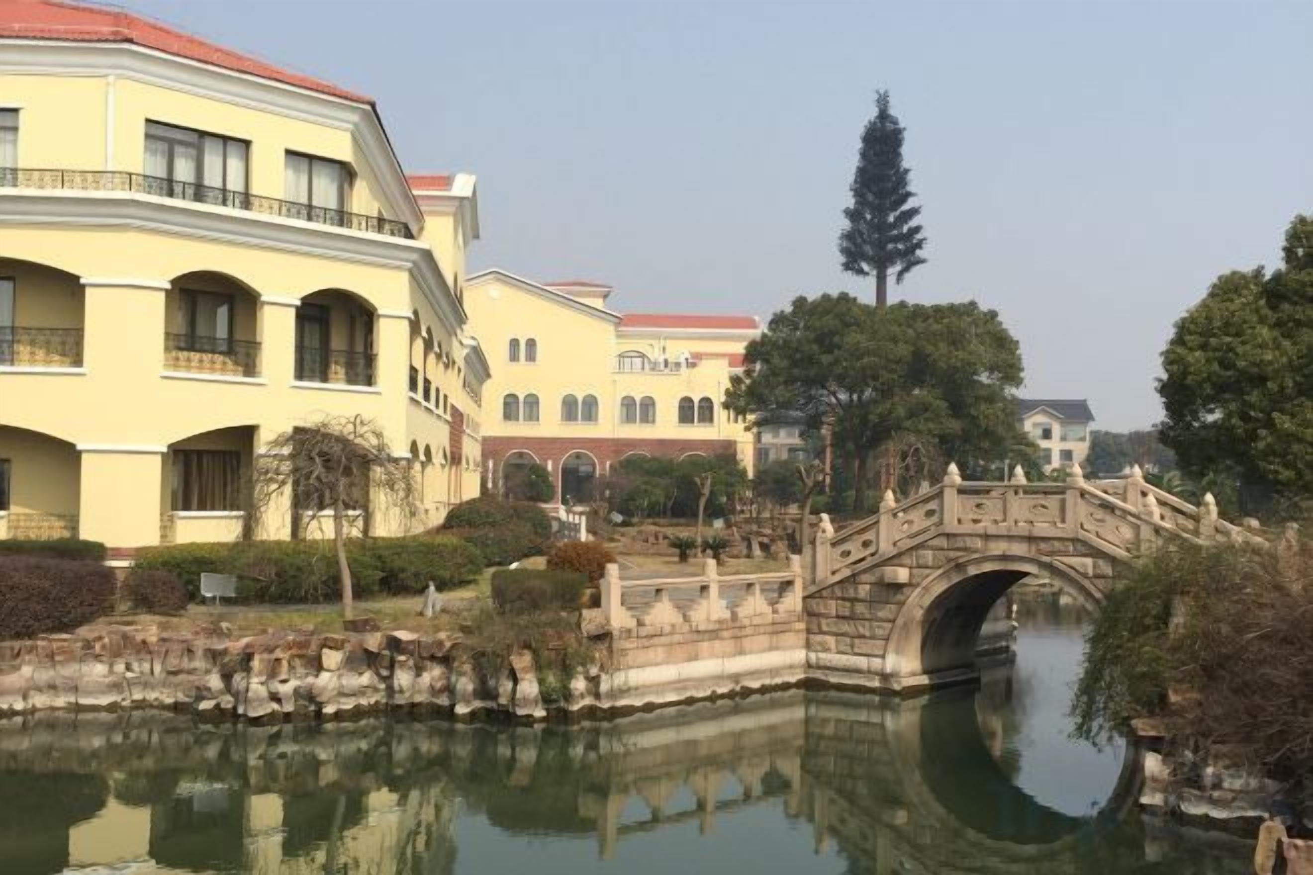 A courtyard with a bridge over a canal, surrounded by buildings with arched windows and balconies.
