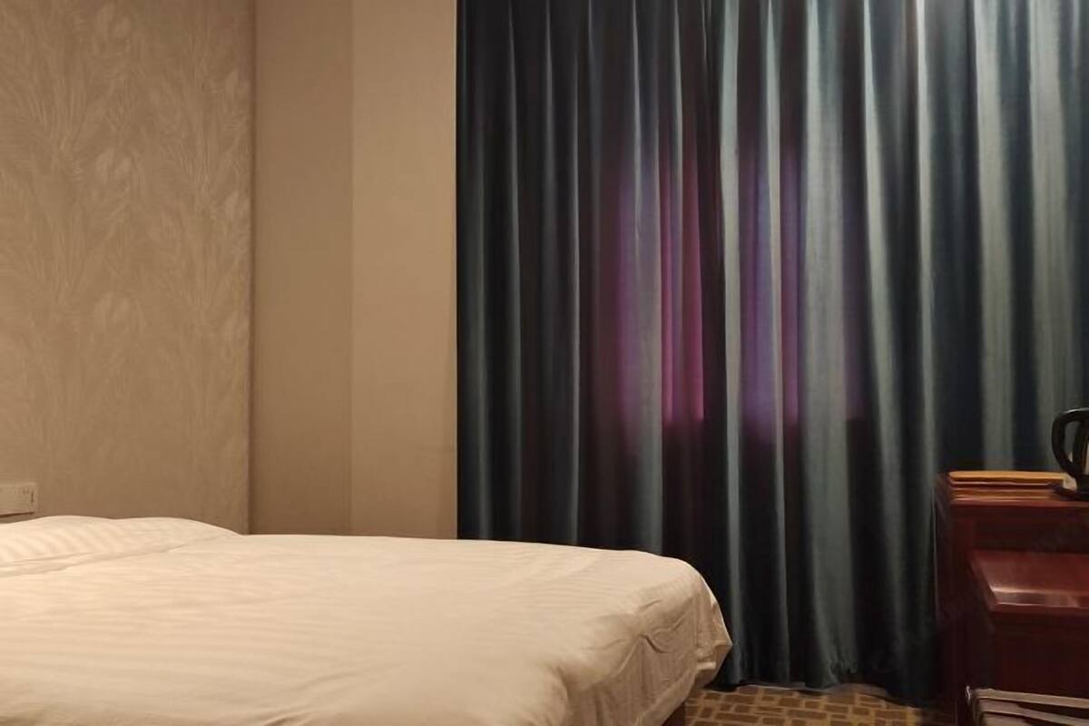 Een hotelkamer met een bed, een bureau en een raam met gordijnen.