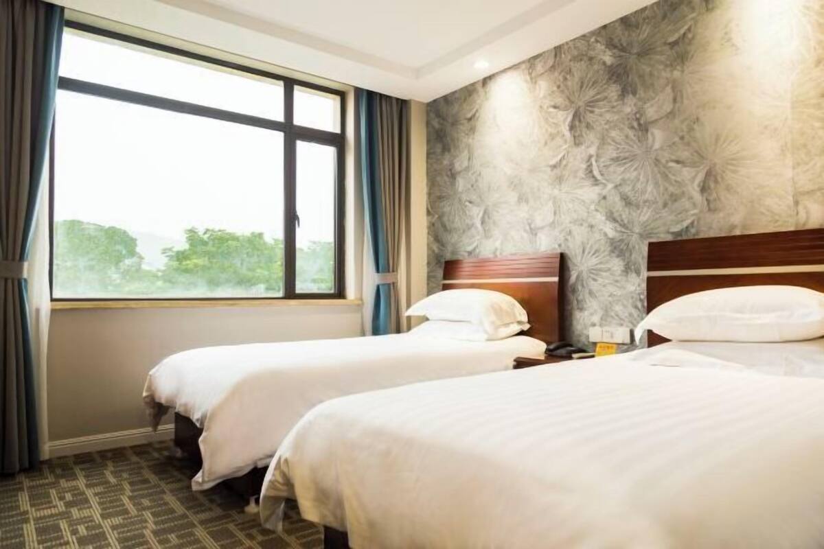 Een hotelkamer met twee bedden, een groot raam en een structuurwand.