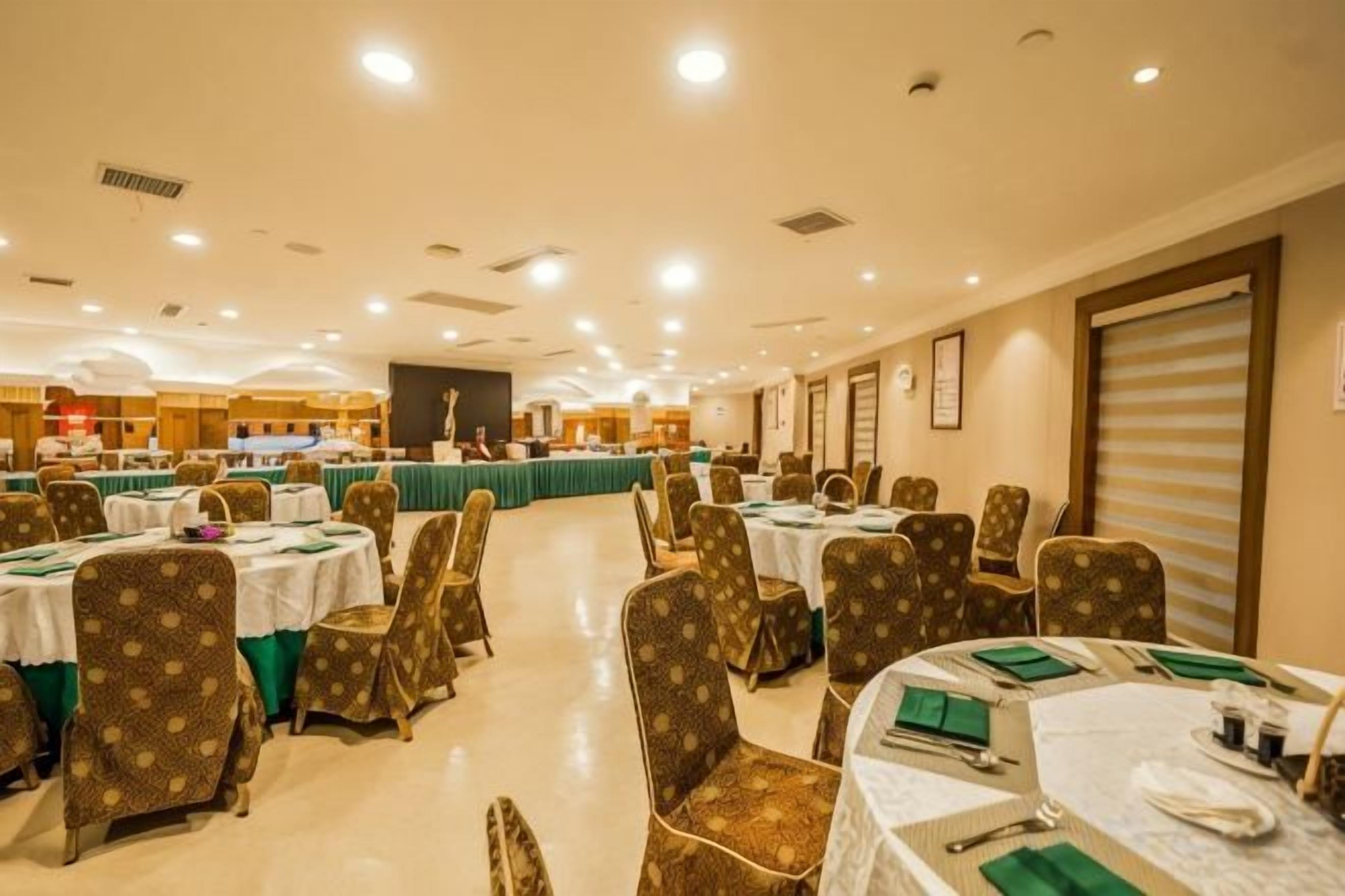 A banquet hall with round tables and chairs, a stage, and a counter.
