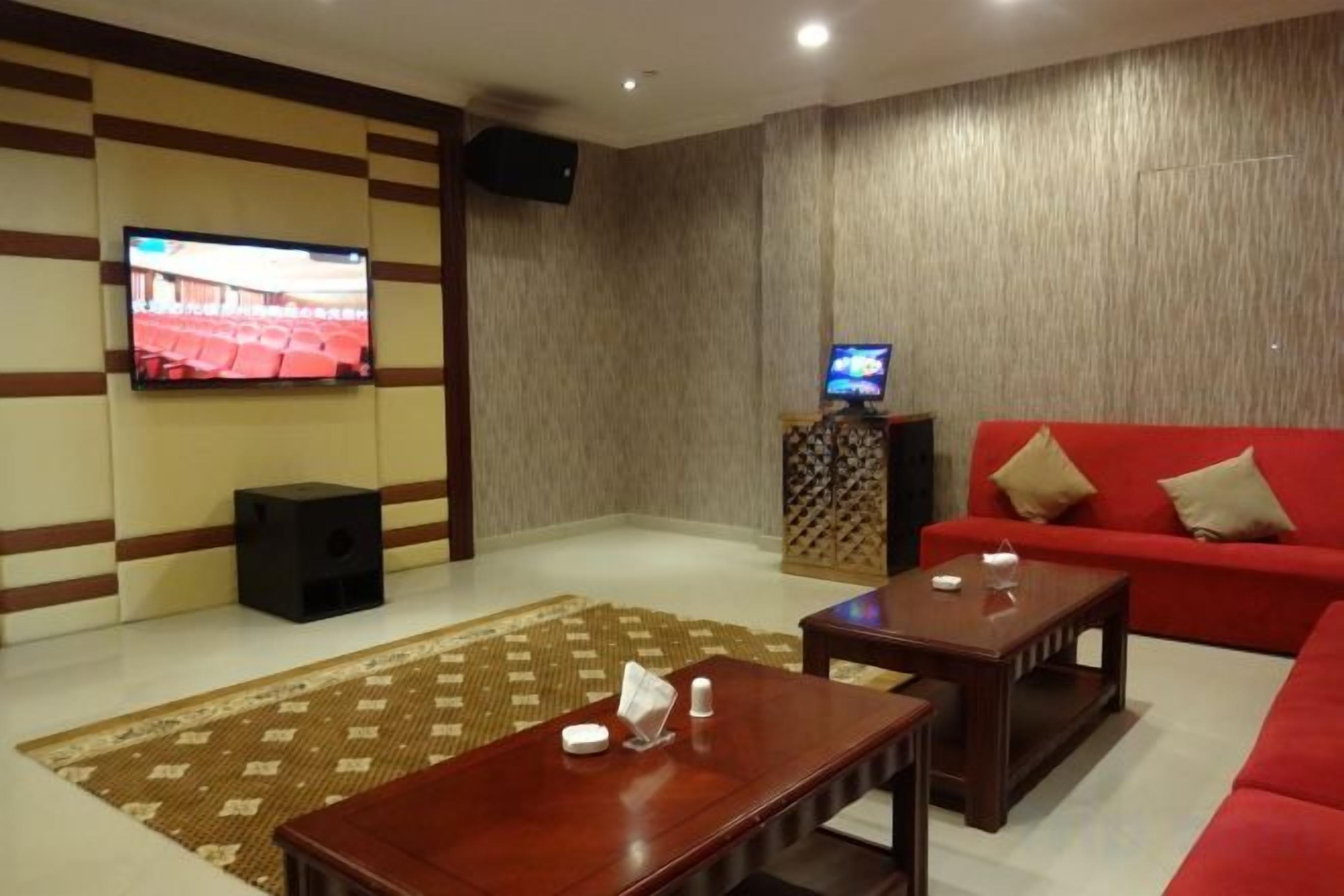 A living room with a flat-screen TV, a red sofa, a wooden coffee table, and a patterned rug.