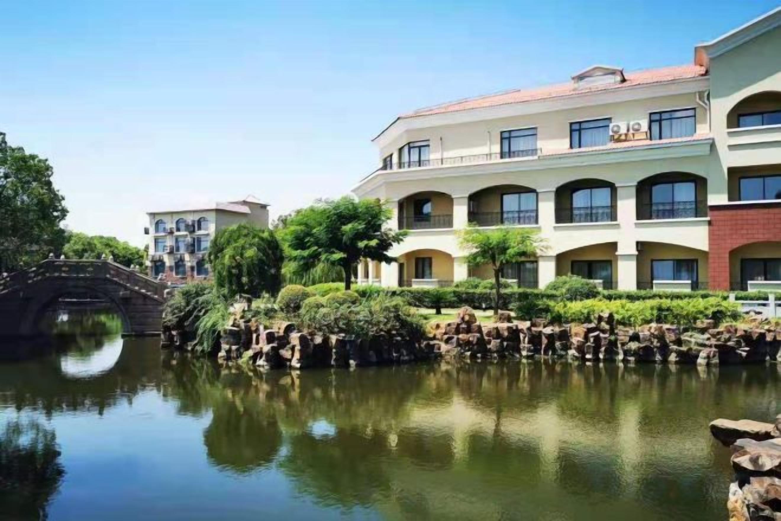 A hotel with a courtyard, a bridge, and a pond.