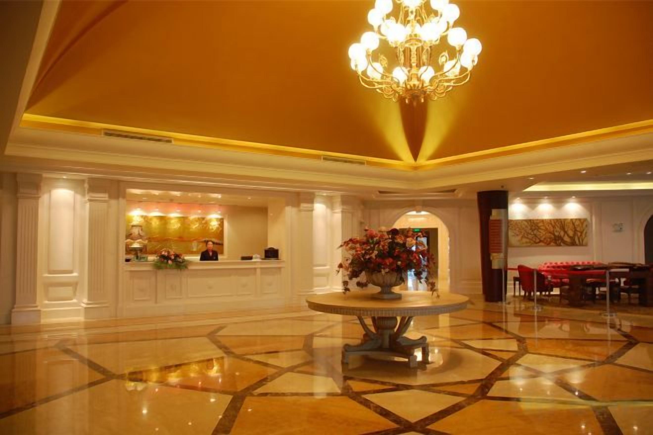 Un vestíbulo de hotel con una recepción, un candelabro y un comedor.