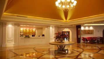 Un vestíbulo de hotel con una recepción, un candelabro y un comedor.
