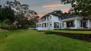 A two-story white building with a covered porch and a well-maintained lawn.