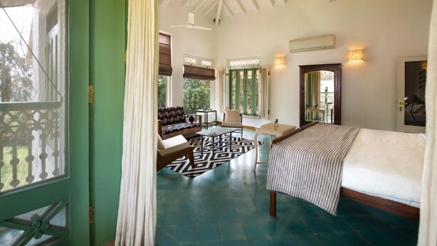 A spacious room with a large bed, a sofa, a small table, and a patterned rug.