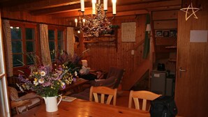 L’intérieur d’un chalet en bois chaleureux et accueillant, avec une table à manger, des chaises, un lustre et un vase à fleurs.