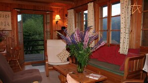 L’intérieur d’un chalet accueillant, avec un décor en bois, une table à manger agrémentée d’un vase de fleurs, un canapé et un fauteuil.