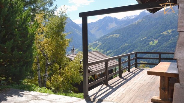 Une terrasse en bois dotée d’un sol en pierre, offrant une vue sur un paysage montagneux.
