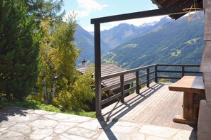 Une terrasse en bois dotée d’un sol en pierre, offrant une vue sur un paysage montagneux.