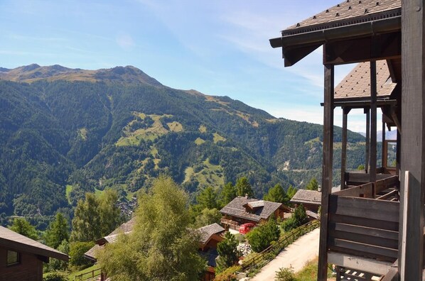 A mountain cabin with a wooden structure and a view of a valley.