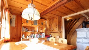 Ein rustikales Interieur mit Esstisch, Bücherregalen und einem Steinkamin.
