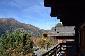 A wooden cabin with a balcony overlooking a mountainous landscape.