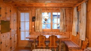 A wooden cabin with a dining table, chairs, and a bench.