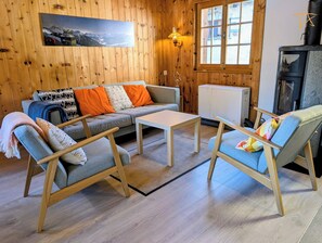 Une pièce chaleureuse avec un mur en bois, un canapé, une table basse et un fauteuil.