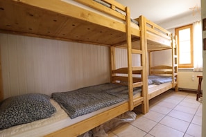 Habitación con literas, ventana, paredes de madera y suelo de baldosas.