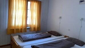 Una habitación con dos camas, una ventana con cortinas y un enchufe.