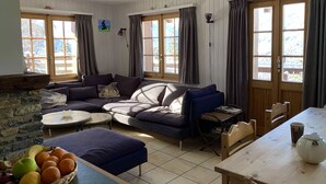 Una sala de estar acogedora con un sofá seccional, una mesa de comedor y una chimenea de piedra.