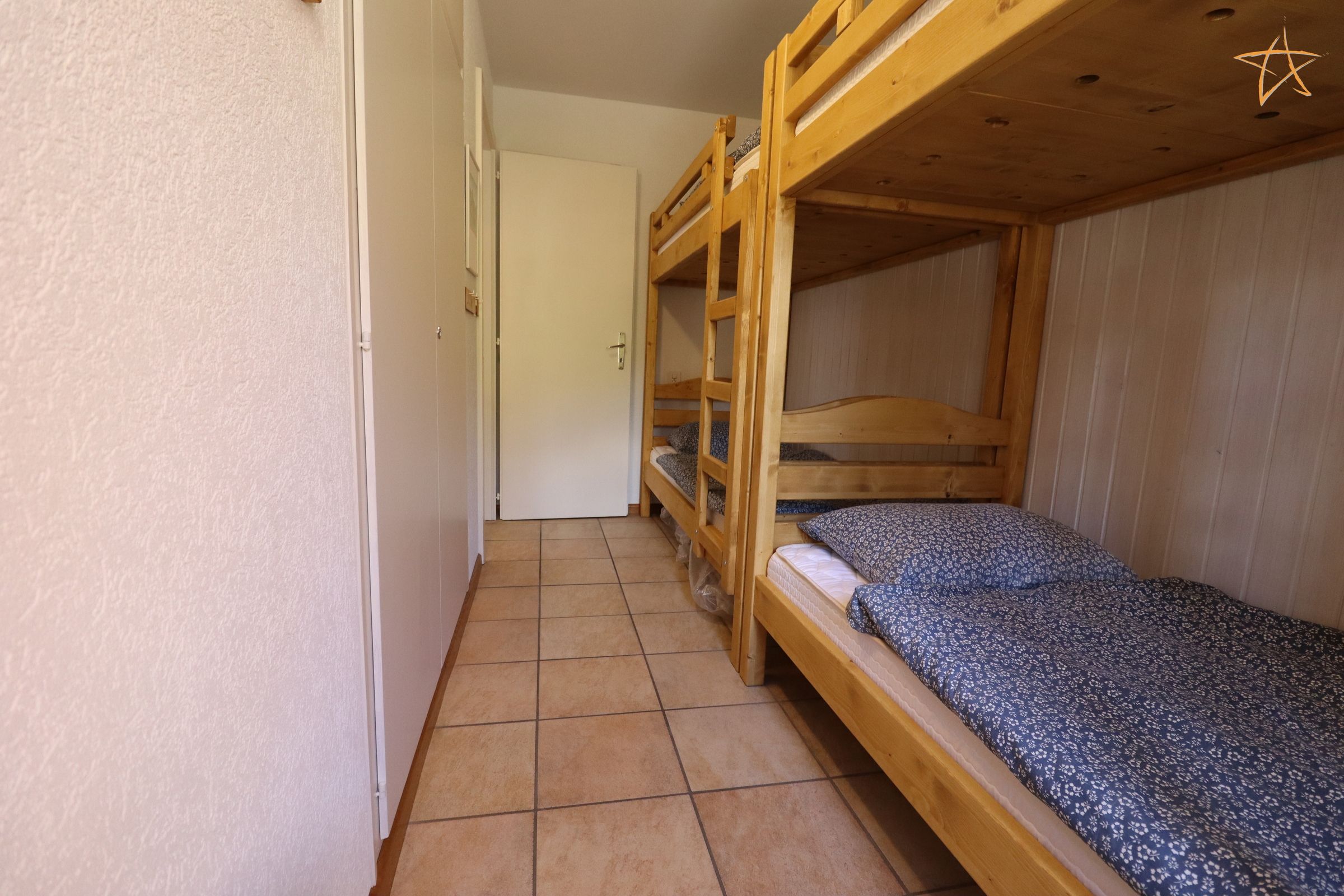 A narrow hallway with bunk beds on one side and a door on the other.