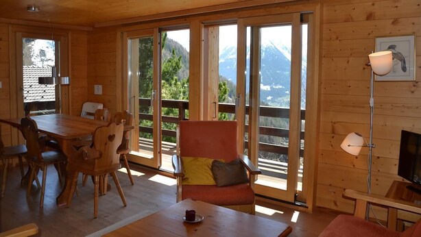 Ein Holzblockhaus-Interieur mit Essbereich, einer Couch und einem Fernseher.