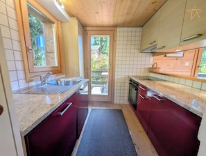 Eine Küche mit Fenster, Spüle, Herd und Schränken.