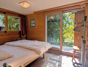 Une chambre à coucher avec un lit, une fenêtre et une porte donnant sur un espace extérieur.