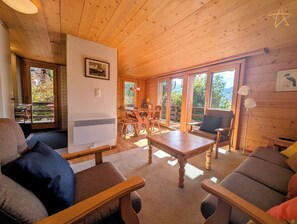 L’intérieur d’un chalet en bois comprend un coin repas, un canapé et une table.