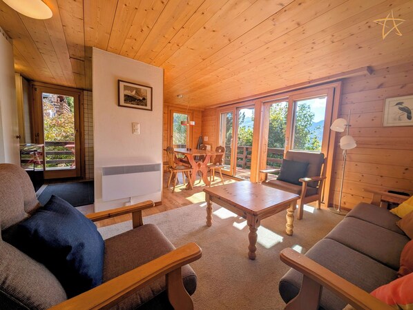 Ein Holzblockhaus-Interieur mit Essbereich, einer Couch und einem Tisch.