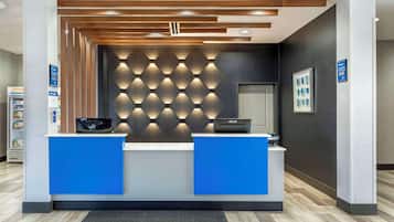 Ein Empfangsschalter mit modernem Design, der durch eine blaue Theke und eine strukturierte Wand im Hintergrund gekennzeichnet ist.