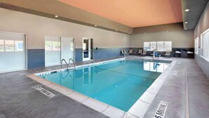 Ein Hallenbad mit klarem Wasser, gefliestem Boden und einer Decke mit Einbaustrahlern.