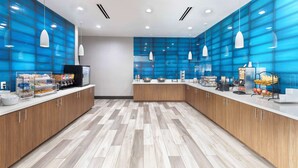 Eine moderne Küche mit Holzschränken, einer weißen Arbeitsplatte und blauen Glasfeldern an den Wänden.
