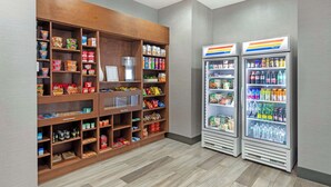 Ein Verkaufsautomatenbereich mit Snacks und Getränken, darunter ein Kühlbereich für Erfrischungsgetränke und ein Regal mit verschiedenen Snacks.