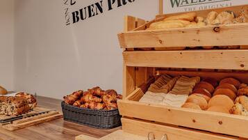 Una exhibición de panadería con diversos panes y pasteles en cajas y cestas de madera.